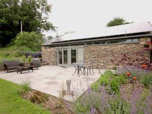 a garden with a patio and a stone building at Mugwell Barn in Callington