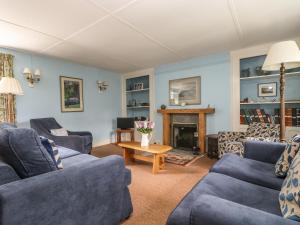 a living room with two blue couches and a fireplace at Polcreek Farmhouse in Veryan