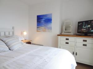a bedroom with a white bed and a tv at Kingfisher Cottage in Wadebridge