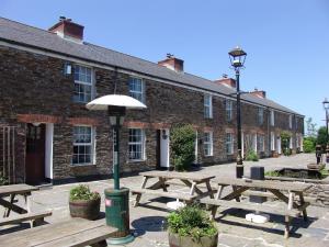 a group of picnic tables in front of a brick building at Kingfisher Cottage in Wadebridge