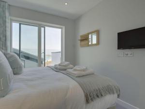 a white bedroom with a large bed with towels on it at Rosen in Crantock