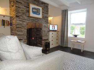 a living room with a couch and a stone fireplace at Kingfisher Cottage in Wadebridge
