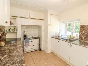 a kitchen with white cabinets and a sink at Nanvivian in Feock