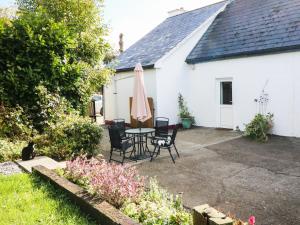 een patio met een tafel en stoelen en een huis bij Julie's Cottage in Castleisland