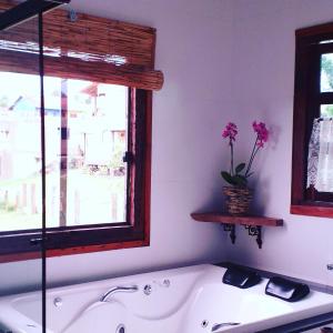 a bath tub in a bathroom with a window and flowers at Brisa de Lavras in Lavras Novas