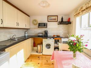 een keuken met een wastafel en een wasmachine bij Julie's Cottage in Castleisland