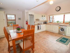 a kitchen with a table and chairs and a clock on the wall at Mary Agnes Cottage in Eyeries