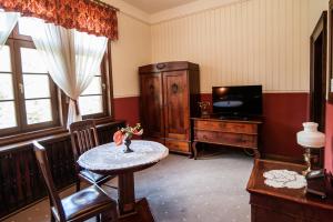 a living room with a table and a tv at Pałac Myśliwski w Antoninie in Antonin