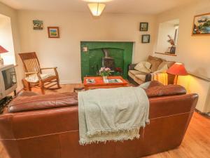 uma sala de estar com um sofá de couro castanho e uma lareira em Nana's House em Eyeries