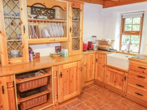 una cocina con armarios de madera y fregadero en Willowbrook Cottage, en Ballyshannon