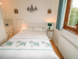 a white bed in a room with a window at 1 Ard Carraig in Portsalon