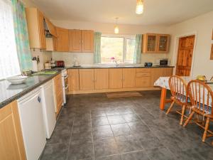 una cucina con armadi in legno, tavolo e sedie di Gapple Cottage a Ballyboe