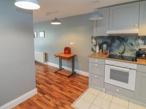 a kitchen with white cabinets and a wooden floor at Silver Birch House in Laune Bridge
