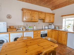 eine Küche mit Holzschränken und einem Holztisch in der Unterkunft Rose Cottage in Ramsgrange