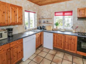 una cocina con armarios de madera y electrodomésticos blancos en Seaspray en Renvyle