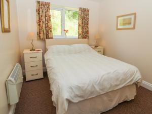 a bedroom with a white bed and a window at Gwern Tyno in Colwyn Bay