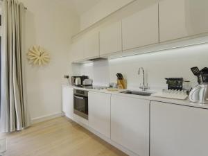 a white kitchen with white cabinets and a sink at Grooms Cottage in Talaton