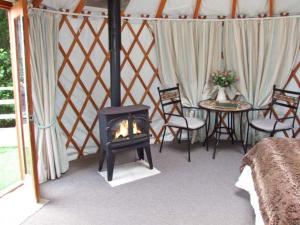 a room with a fireplace and a table and chairs at The Lakeside Yurt in Tewkesbury