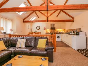 a living room with a leather couch and a kitchen at The Old Stable in Sidbury