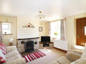 a living room with a fireplace and a tv at Marsh Cottage in Ashbourne