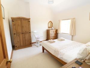 a bedroom with a bed and a dresser and a window at Marsh Cottage in Ashbourne