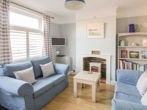 a living room with a blue couch and a fireplace at Sea Breezes in Lowestoft