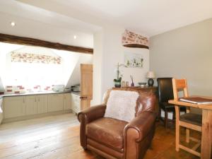 a living room with a leather chair and a table at Edenbank Cottage in Carlisle