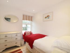 a bedroom with a bed and a dresser and a mirror at Dale Cottage in Crantock