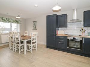 a kitchen with black cabinets and a table and chairs at Tremfor in Rhosneigr