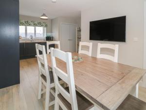 a kitchen and dining room with a wooden table and chairs at Tremfor in Rhosneigr