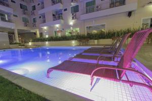 Eine Gruppe von Stühlen, die um ein Schwimmbecken herum angeordnet sind in der Unterkunft Bombinhas Summer Beach -Apartamento Particular in Bombinhas