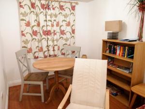 una mesa y sillas en una habitación con cortina en 4 Bredon Court, en Newquay 4 fotos más