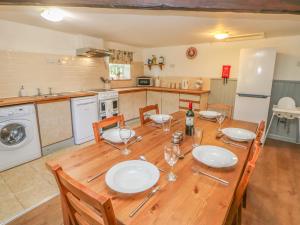 a kitchen with a wooden table with plates and wine glasses at Witton View Cottage in Bishop Auckland