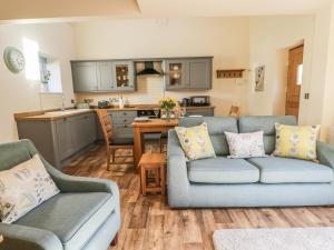 a living room with two couches and a kitchen at The Hayloft in Husthwaite