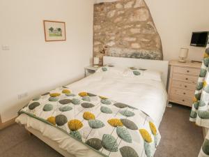 a bedroom with a bed with a quilt on it at Herdwick Cottage in Grange Over Sands