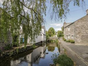 a canal in a village with houses and trees at Herdwick Cottage in Grange Over Sands