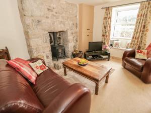 a living room with a leather couch and a fireplace at Herdwick Cottage in Grange Over Sands