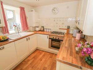 a kitchen with a sink and a stove top oven at Herdwick Cottage in Grange Over Sands