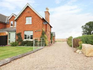 a brick house with a gravel driveway at Chippers Cottage in Woodhall Spa