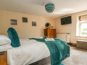 a bedroom with a bed with a green blanket on it at Ashknott Cottage in Ripon