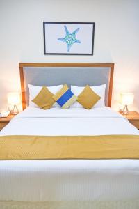 a bed with a white comforter and two pillows at City Stay Grand Hotel Apartments - Al Barsha in Dubai