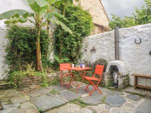 two red chairs and a table in front of a building at Primrose Cottage in Penryn