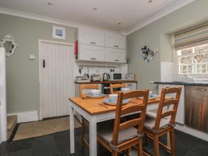 cocina con mesa de madera y sillas en Primrose Cottage, en Penryn