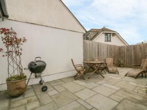 a patio with a grill and a table and chairs at The Bolthole in Crantock