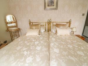 1 dormitorio con 1 cama grande con sábanas y almohadas blancas en Daisy's Holiday Cottage en Skipton