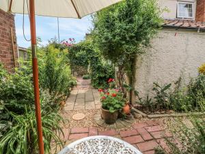 a patio with an umbrella and some plants and flowers at Megs Cottage in Norwich