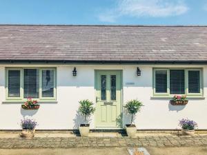 ein weißes Haus mit grüner Tür und Topfpflanzen in der Unterkunft Orchard Cottage in Holywell