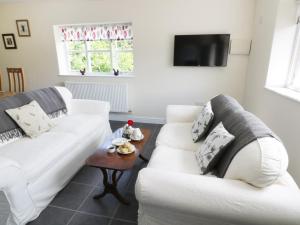 a living room with two white couches and a table at The Hen House in Bromyard