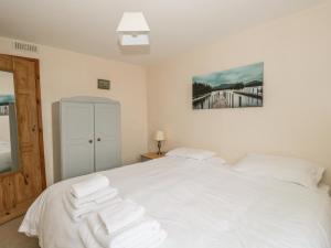 a bedroom with a white bed with towels on it at 1 Park Nook Close in Waberthwaite