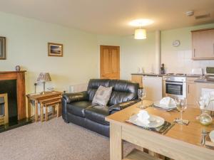 a living room with a leather couch and a table at 2 Park Nook Close in Waberthwaite